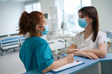 Uzman doktorlar resüsitasyon odasındaki masada hastaların analizini tartışıyorlar.