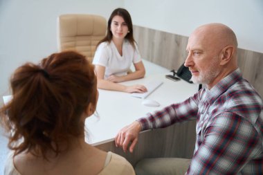 Kadın doktor nüanslardan bahsediyor ve gelecekteki ailelere hastanede hamilelik konusunda güvence veriyor.