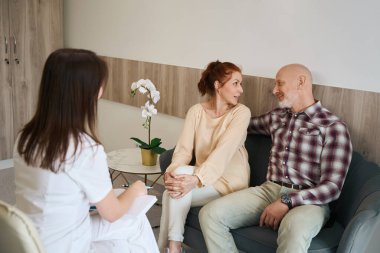 Klinikteki sağlık dolabında bebek bekleyen hastalarla iletişim kuran kadın doktor.