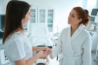 Hastanedeki muayeneden sonra hastasını destekleyen ve ellerini tutan kadın doktor.