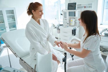 Klinikteki muayeneden önce jinekolog koltuğunda hastasını destekleyen kadın jinekolog.