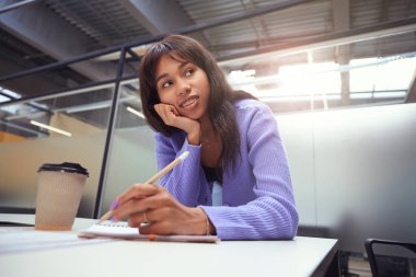 Kapalı alanda kalem kullanarak fotokopi kitabına yazarken diş teli takan güzel bir kadın.