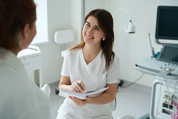 Lächelnde Ärztin Gespräch Mit Ihrer Patientin Und Notizbuch Mit Ratschlägen — Stockfoto