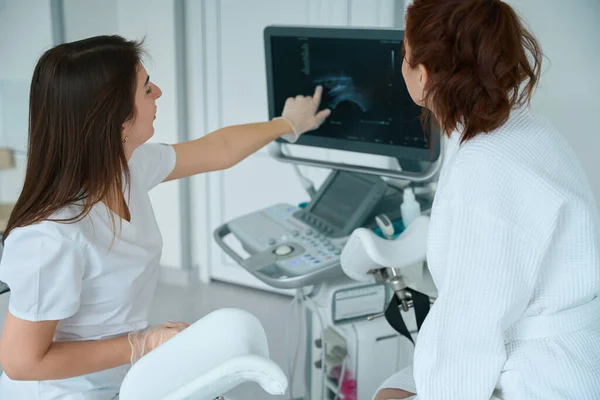 临床超声扫描仪屏幕显示女性患者超声图像的专业医生 — 图库照片