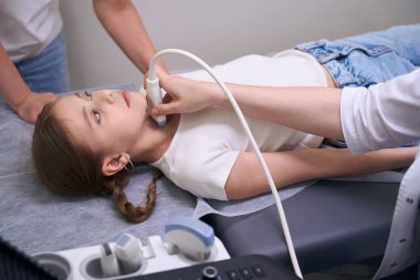 Tiroid bezinin ultrasonu için klinikteki genç hasta, teşhis uzmanı modern ekipman kullanıyor.