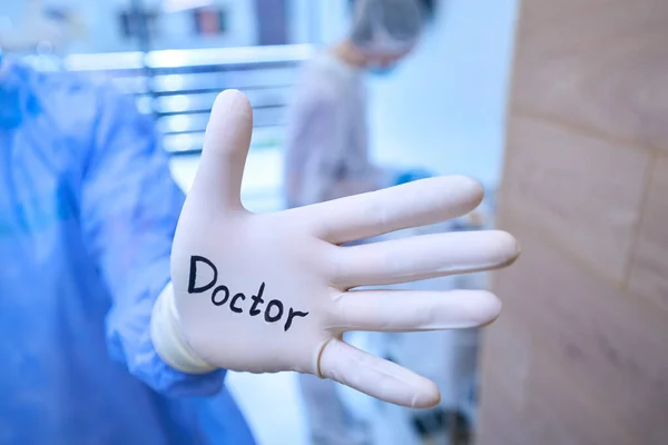 手术室里的外科医生 戴着印有 字样的一次性手套 旁边坐着一位女性助手 — 图库照片