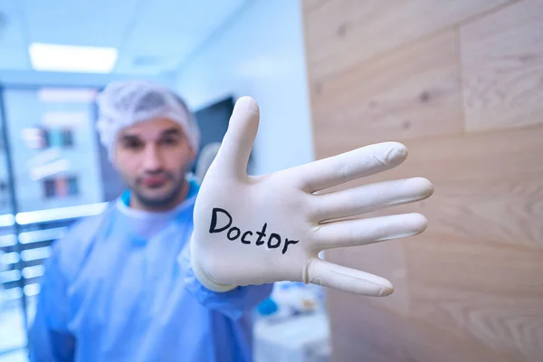 医師の碑文と使い捨て手袋の男性外科医 女性のアシスタントの隣に — ストック写真