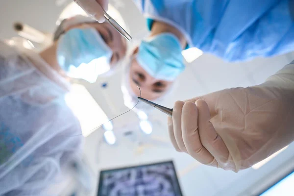 Młody Chirurg Trzyma Rękach Specjalną Igłę Chirurgiczną Pobliżu Jest Asystentka — Zdjęcie stockowe