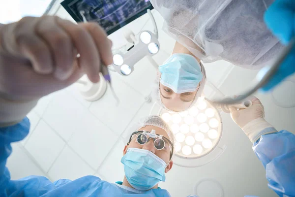 在手术室的工作场所 一位戴特殊镜片的外科医生的女助手正在帮他 — 图库照片