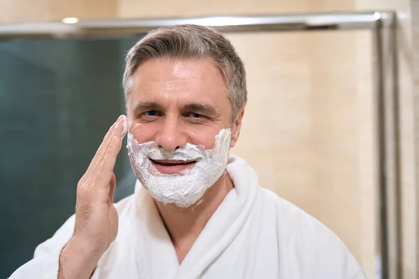 Homem Adulto Casaco Branco Aplica Espuma Rosto Banheiro Olhando Para — Fotografia de Stock