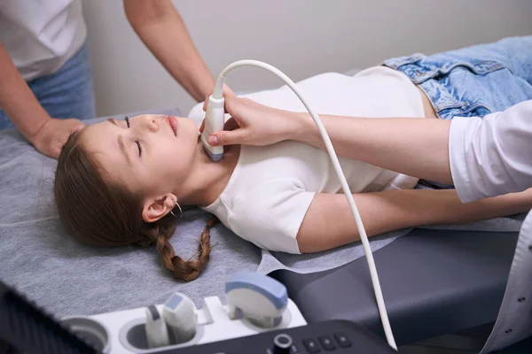甲状腺の超音波のための診療所でピグテールを持つ女の子 診断は 現代的な機器を使用しています — ストック写真