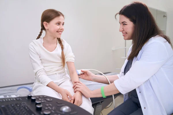 優しい女性医師は 若い患者の超音波検査を行い 医師は肘関節で動作します — ストック写真