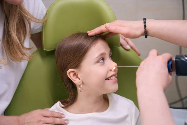 女性の耳鼻咽喉科医は 女の子の母親の隣に 少し患者の鼻を調べます — ストック写真