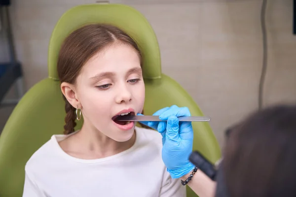 戴防护手套的女医生用特殊的工具检查小孩的喉咙 — 图库照片