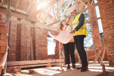 Uzman inşaat mühendisleri çelik yelek giyip uzay dağıtımından bahsediyorlar, binanın içinde inşaat halindeler.