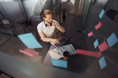 Sakallı adam rahatça bir ofis bloğundaki işyerine yerleşti. İnternetten iletişim kuruyor.