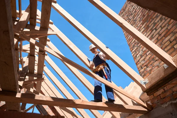 天井構造物の梁を支える上を歩く女性建築技術者建築現場で働く建築品質をチェックする — ストック写真