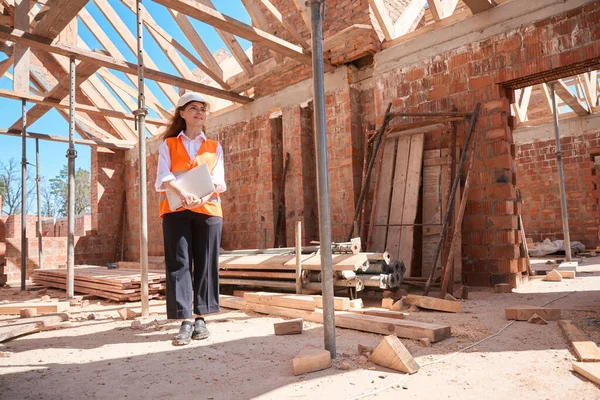 ラップトップで建設中の建物の中を歩くハードハットの責任ある女性建築技術者 建物の品質をチェック — ストック写真