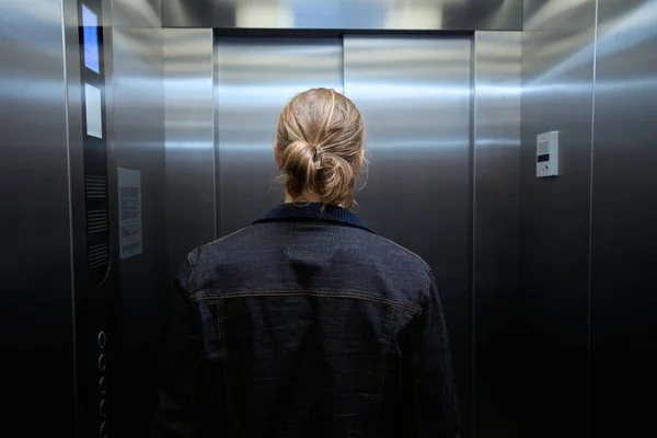 穿着斜纹棉布夹克的男人在乘客电梯舱 左边是带有楼层选择按钮的面板 — 图库照片
