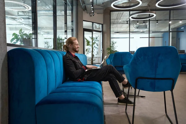 Bearded Man Sitting Blue Sofa Recreation Area Texting Laptop — Stock Photo, Image