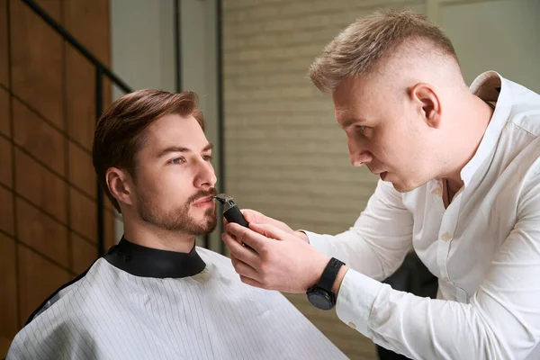 Kaukasischer Friseur Schneidet Bart Schöner Besucher Mit Rasiermesser Modernem Salon — Stockfoto