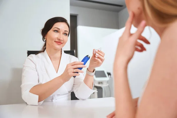 Uzman Estetisyen Müşteriye Etkili Bir Bakım Ürünü Sunuyor Kozmetik Kliniğinde — Stok fotoğraf