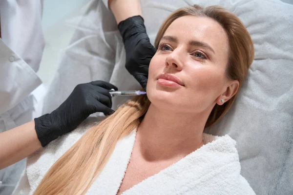 Female Receives Rejuvenating Injection Her Cheeks Esthetician Works Protective Gloves — Stock Photo, Image