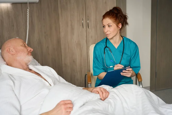 Kvinnlig Läkare Uniform Sitter Med Urklipp Nära Patienten Som Ligger — Stockfoto