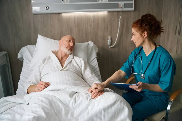 Krásná Lékařka Stetoskopem Povzbuzuje Svého Pacienta Který Leží Posteli Drží — Stock fotografie