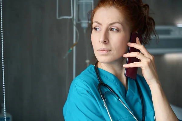 Koncentrerad Kvinnlig Läkare Med Stetoskop Talar Smartphone Kammaren Kliniken — Stockfoto