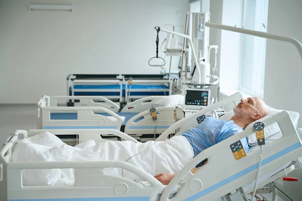集中治療室で呼吸器系のヘルプを取得し ベッドの上に横たわる非常に病気の男 — ストック写真