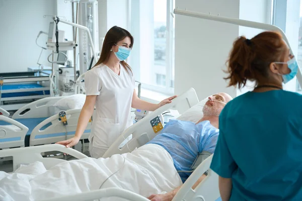 Enfermeras Cuidando Paciente Masculino Que Yace Cama Del Hospital Sala —  Fotos de Stock