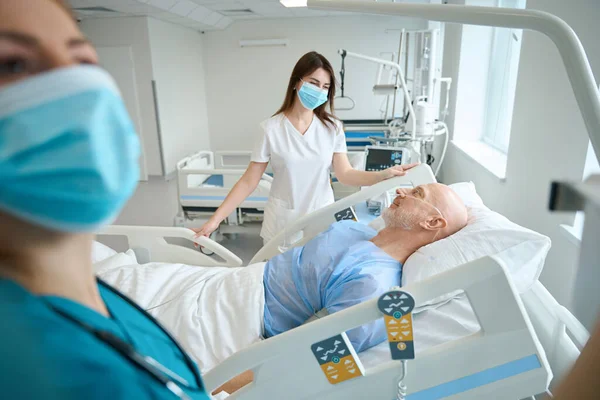마스크를 치료사들 응급실에서 침대에 환자의 상태를 진단하기 장비를 화하는 — 스톡 사진