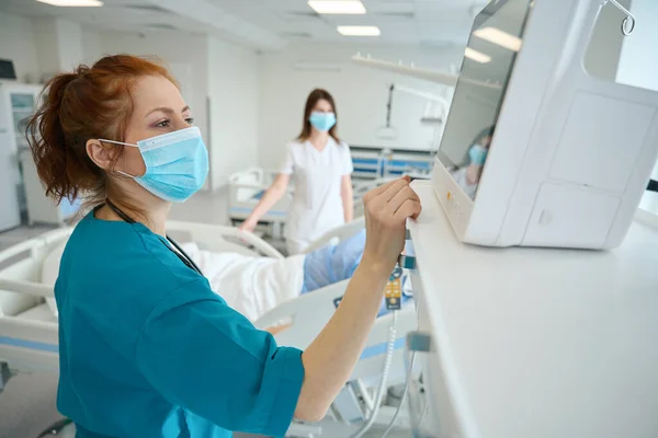 Kobiecy Anestezjolog Dostosowujący Pulsometr Podczas Komunikacji Chirurgicznej Pacjentem Operacji Jednostce — Zdjęcie stockowe
