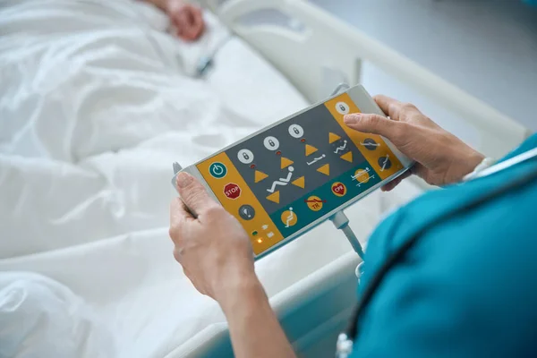救急室の電気的に調節可能なベッドのリモコンパネルの医師の手押しボタンのクローズアップ — ストック写真