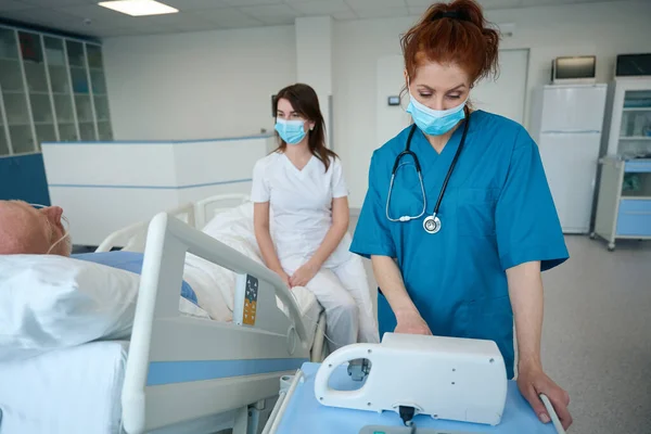 간호사는 의사가 환자에게 환자에게 요청하는 침대에 중환자를 치료를 펌프를 — 스톡 사진