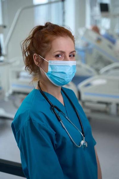 集中治療室に立つ聴診器を持つ医療用マスク中の自信に満ちた女性医師の肖像 — ストック写真