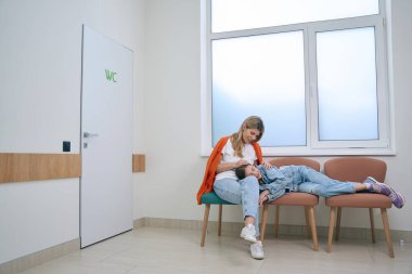 Sarışın ve kızı pencerenin yanındaki bekleme salonuna yerleşti. Annesi kızı teselli etti.