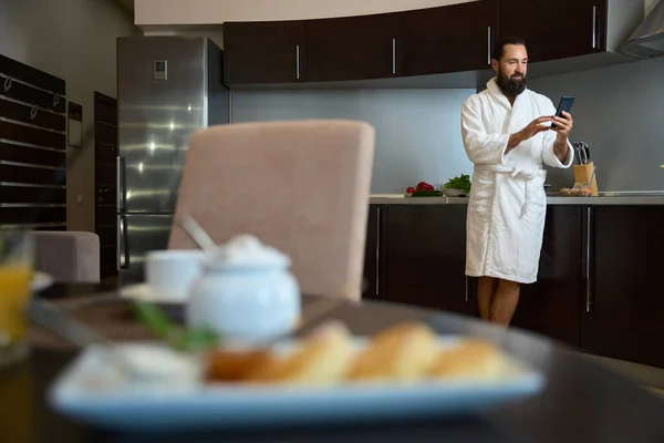 Sakallı Erkek Mutfak Alanında Cep Telefonuyla Duruyor Kahvaltı Servisi Başlıyor — Stok fotoğraf