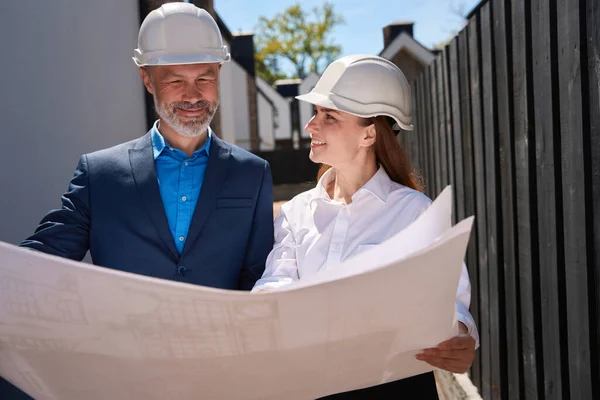ブループリントと笑顔を見る男性と女性建築家 場所と建設開始 住宅開発に満足 — ストック写真