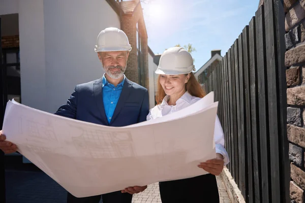Uśmiechnięci Inżynierowie Patrzący Plan Budowy Omawiający Szczegóły Przed Rozpoczęciem Budowy — Zdjęcie stockowe