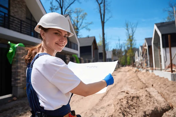 微笑着看草图的女建筑工程师 花时间在建筑工地 为铺石板做准备 — 图库照片