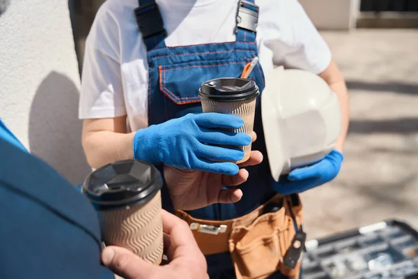 女性ビルダーのエンジニアがコーヒーを飲んで 同僚が建設プロセスを議論し 屋外で飲料を楽しんでいる — ストック写真
