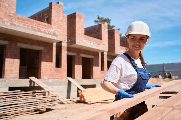 Uśmiechnięta Brygadzistka Twardych Całościowych Belkach Drewnianych Pracująca Drewnem Placu Budowy — Zdjęcie stockowe