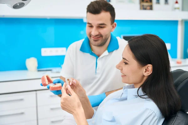 stock image Orthodontist showing to female client transparent dental braces he made using 3d model of her teeth, woman trying on new aligner, aesthetic dentistry