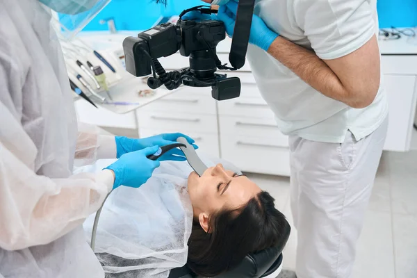 医生在助手的帮助下拍摄了病人的牙齿 该妇女坐在了牙椅上 — 图库照片