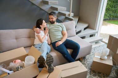 Kafkasyalı bir erkek ve kadın rahat bir kanepede otururken birbirlerine bakıyorlar.