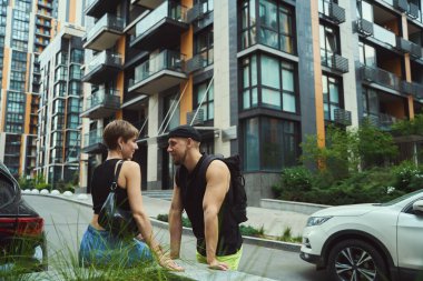 Gündelik giysiler içinde genç bir çift şehir ortamındayken birbirlerine sevgiyle bakıyor.