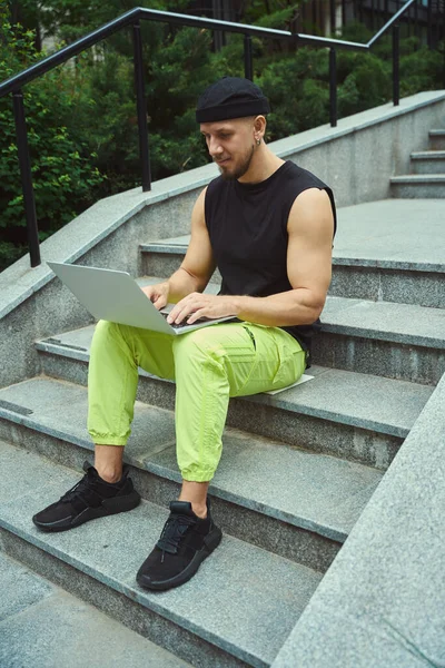 Hezký Muž Neformálním Oblečení Pomocí Notebooku Zatímco Sedí Schodech Venku — Stock fotografie