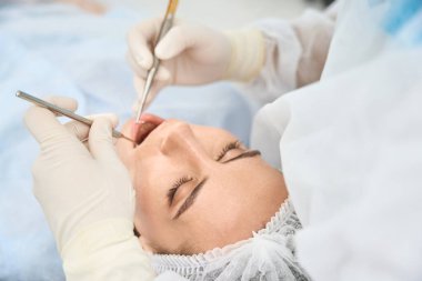 Kadın dişçi randevusunda, doktor diş kanalını temizler.